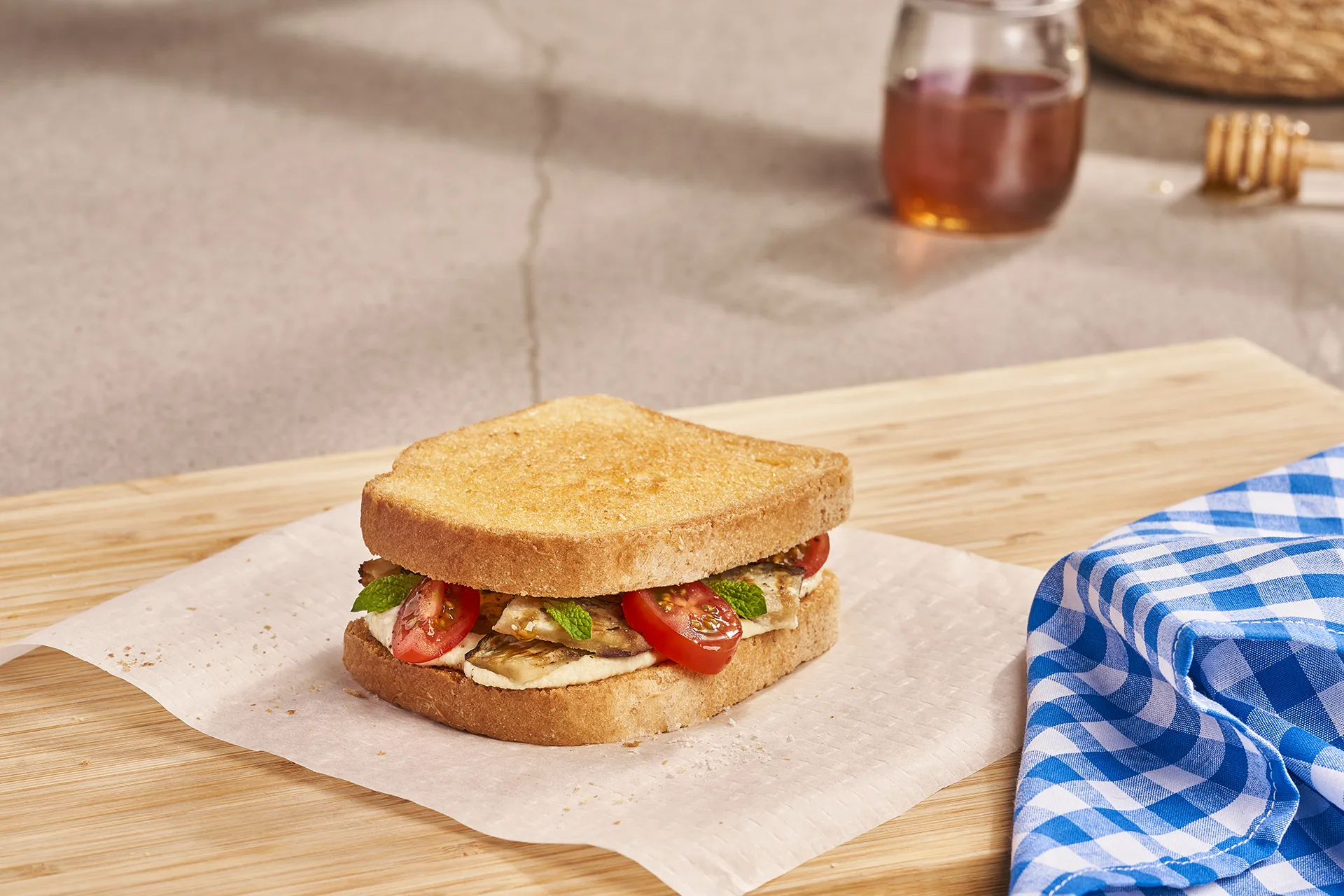 Sándwich de hummus, berenjena asada y tomate cherry con miel